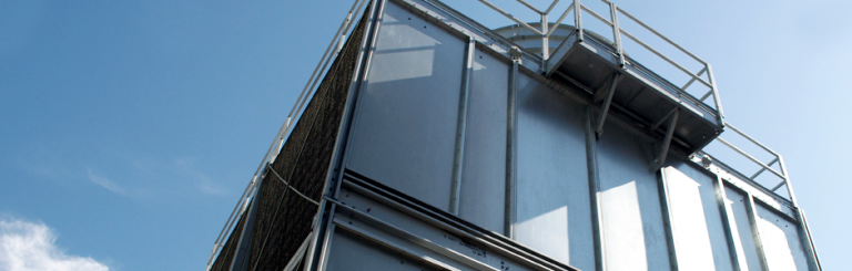 Photo of a cooling tower shot from an extreme low angle with blue sky as its backdrop.