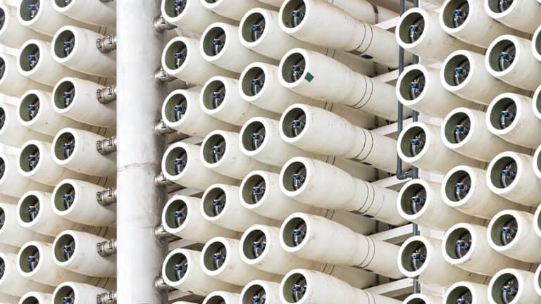 Dense array of white cylindrical reverse osmosis membrane pressure vessels in an industrial water treatment plant.