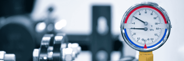 A close-up of a circular industrial dual-scale gauge showing temperature and pressure. The top needle points to approximately 35°C, while the bottom needle indicates a pressure of about 0.05 MPa. The gauge is mounted on a brass fitting against a blurred blue and white industrial background.