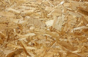 Close-up of Oriented Strand Board (OSB) texture, showing compressed wood strands and flakes.