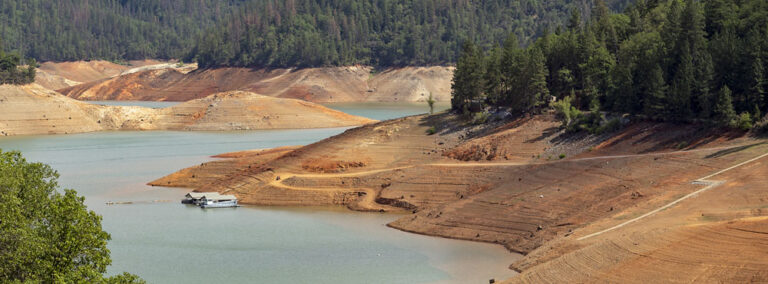 California's Shasta Lake, showcasing significantly low water levels, likely a result of drought conditions, cropped.