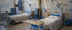 A modern, well-equipped dual patient hospital room featuring two empty beds and medical monitoring equipment.