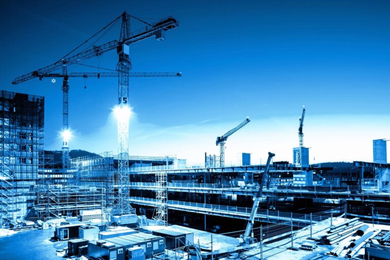 A multi-story building under construction with cranes, stylized with a blue and sepia color treatment.